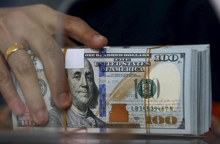 © Reuters. An employee of a money changer holds a stack of U.S.  Dollar notes before giving it to a customer in Jakarta
