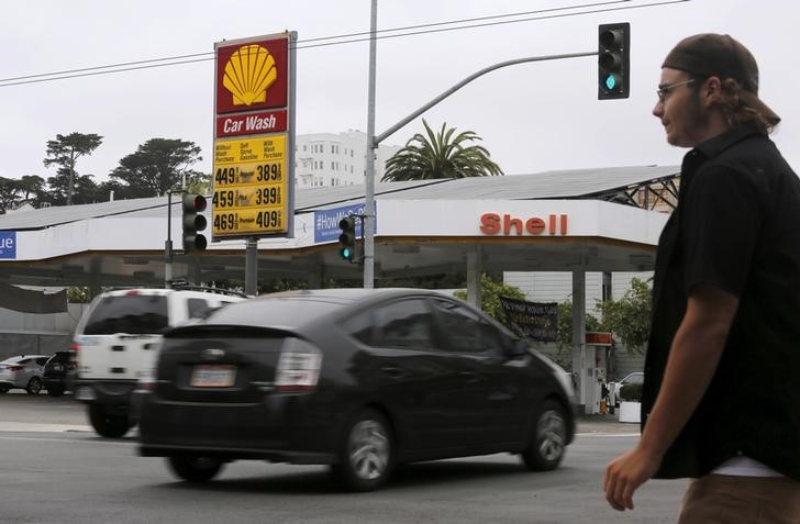 © Reuters. A pedestrian stands near a sign displaying the cost of gasoline at a filling station in San Francisco
