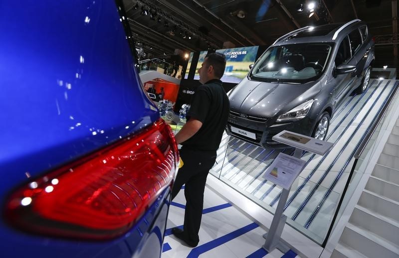 © Reuters. A man walks past a Ford Kuga car during the media day at the Frankfurt Motor Show (IAA) in Frankfurt