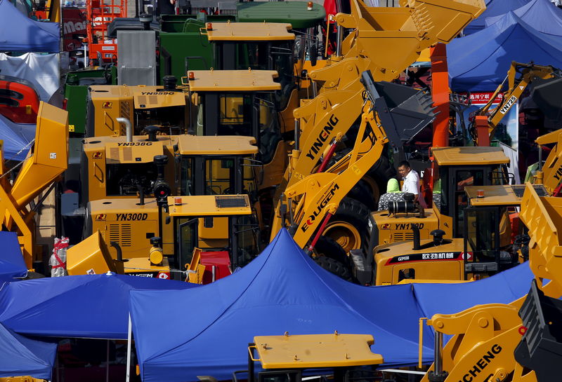 © Reuters. Exhibitor chats with a visitors amidst construction vehicles on display at Canton Fair in the southern Chinese city of Guangzhou