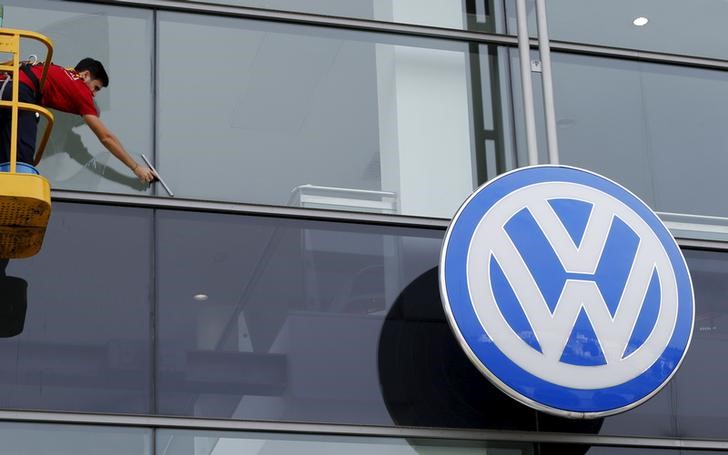 © Reuters. A worker cleans the facade of a Volkswagen dealership near the Andalusian capital of Seville, southern Spain