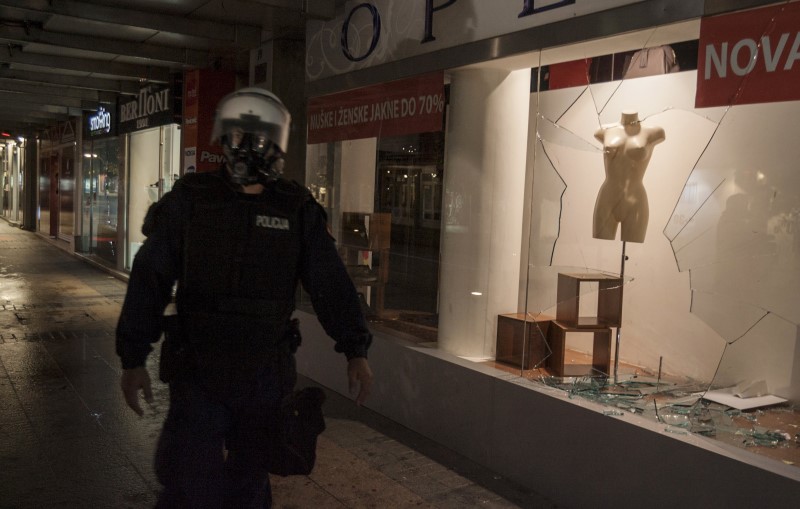 © Reuters. Riot policeman walks past a broken store window after protests in Podgorica, Montenegro