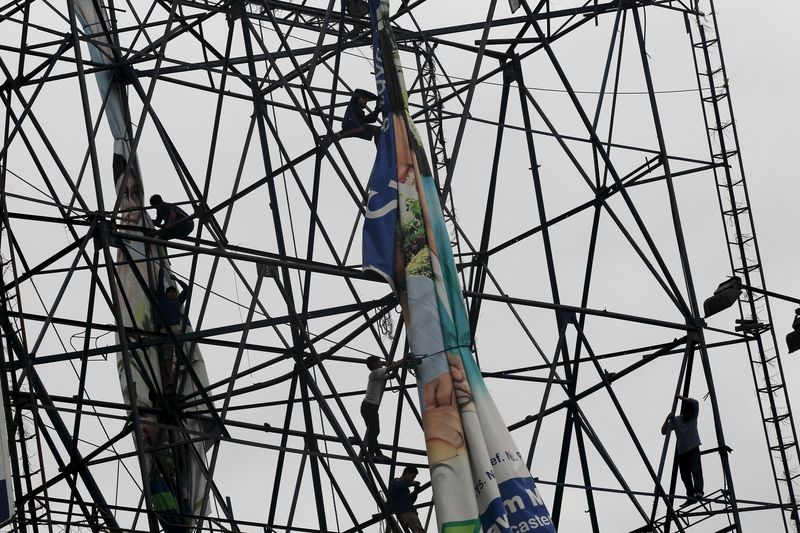 © Reuters. Workers fold a tarpaulin along a highway in preparation for Typhoon Koppu in Paranaque city