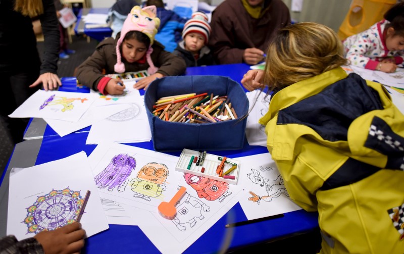 © Reuters. Migrant children colour in a playroom in a refugee camp in Celle