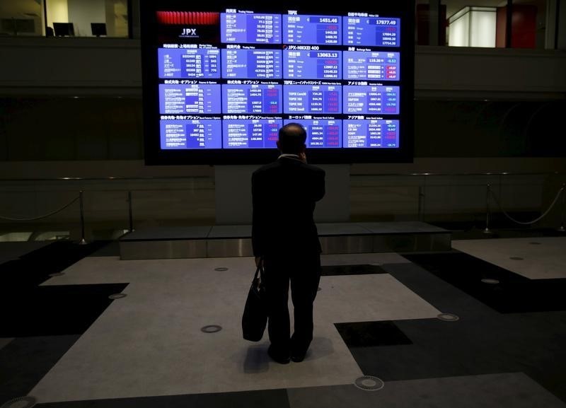 © Reuters. A man looks at an electronic board showing Japan's Nikkei average and related indices at the Tokyo Stock Exchange in Tokyo