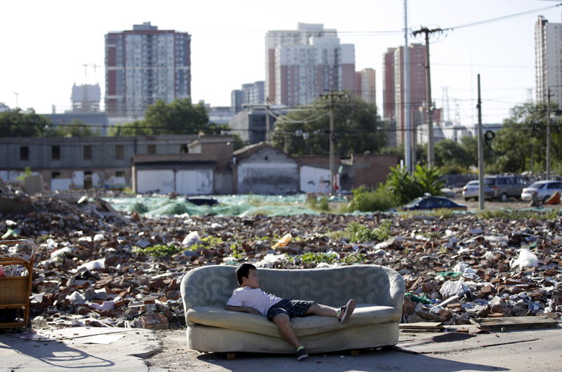 © Reuters. A boy plays on a disused sofa in the ruins in central Beijing