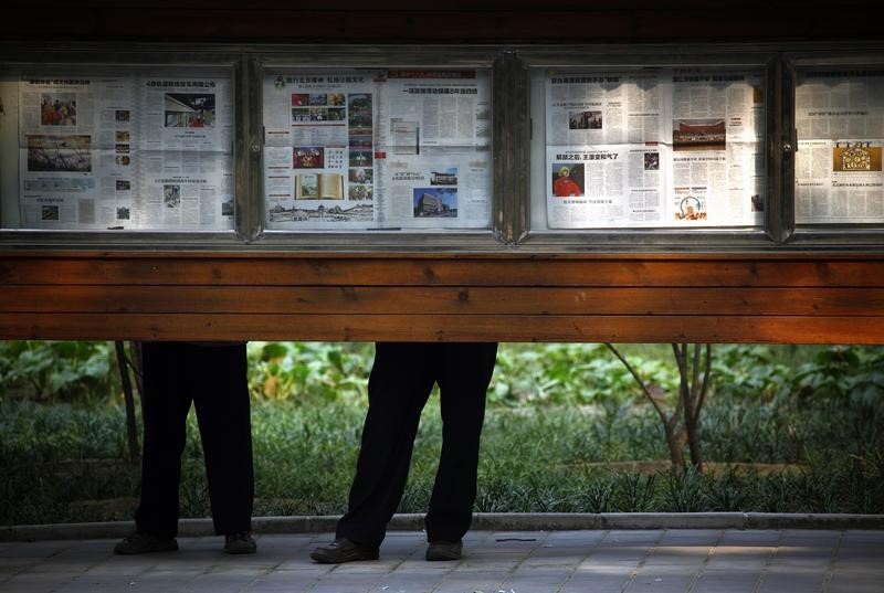 © Reuters. Men read official daily newspapers on display at Ritan Park located in central Beijing