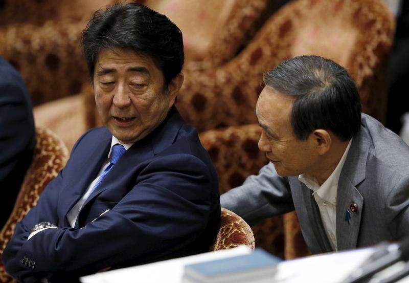 © Reuters. Japan's Prime Minister Abe talks with Chief Cabinet Secretary Suga at a lower house special committee session on security-related legislation at the parliament in Tokyo
