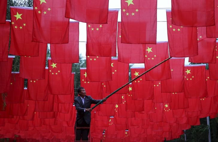 © Reuters. Homem colocando bandeiras chinesas em parque em Pequim