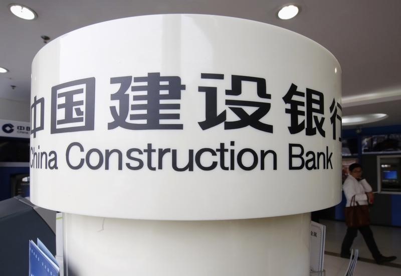 © Reuters. A man walks past a sign of China Construction Bank at its branch in Beijing