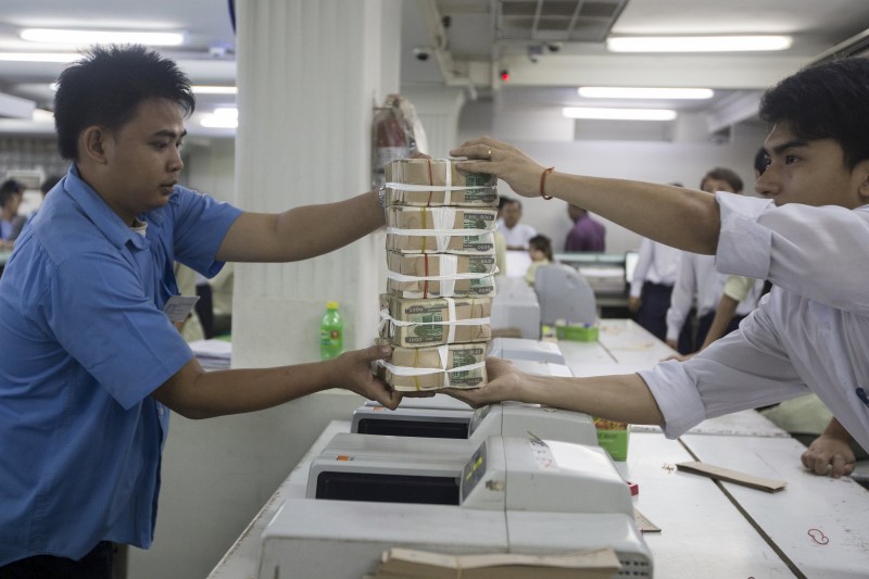 © Reuters. A staff hands a stack of Myanmar Kyat to another at a bank in Yangon