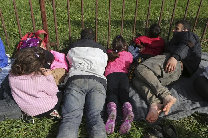 © Reuters. Imigrantes deitados em frente grade em Dobova, na Eslovênia