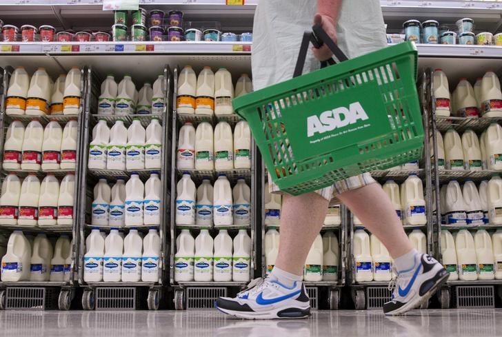 © Reuters. A shopper walks past milk cartons in an aisle of Asda supermarket in London