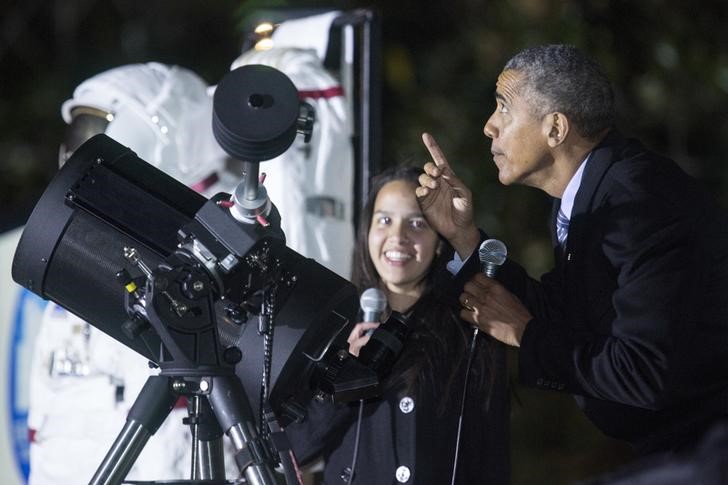 © Reuters. Presidente dos EUA, Barack Obama, aponta para a lua após observar satélite por telescópio em jardim da Casa Branca