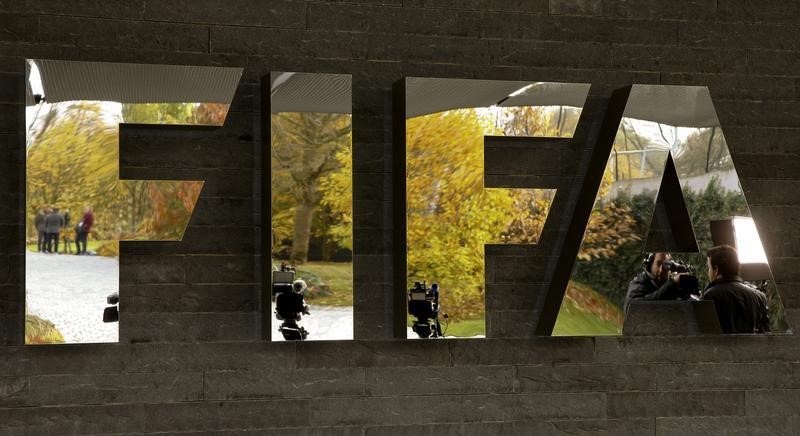 © Reuters. Jornalistas refletidos no logo da Fifa do lado de fora da sede da entidade, em Zurique