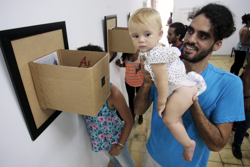 © Reuters. Grafiteiro cubano Danilo Maldonado segura a filha durante exposição de fotos