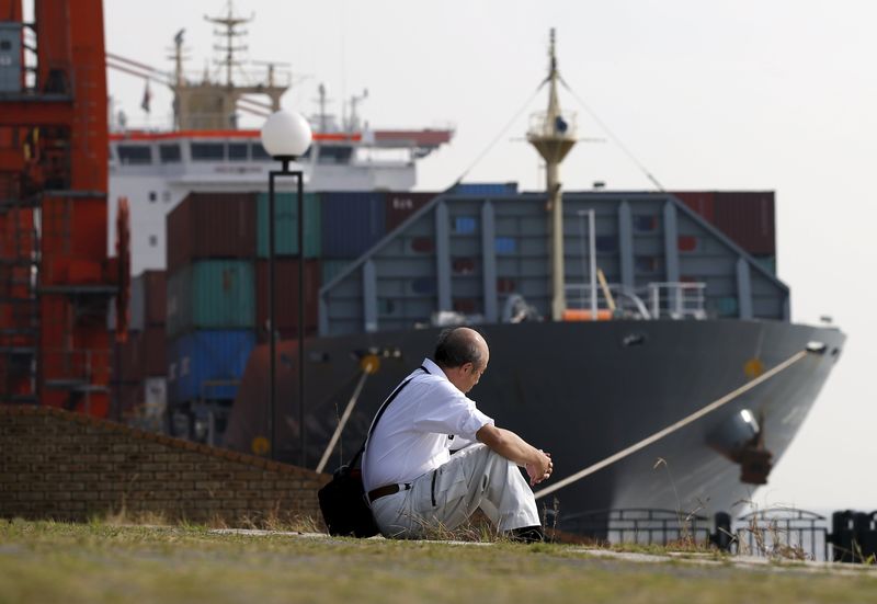 © Reuters. A man sits near a container ship at a port in Tokyo