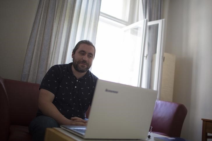 © Reuters. Syrian migrant Mohamad Algahmian looks at family pictures on a laptop in his flat in the "Sharehaus Refugio" community in Berlin