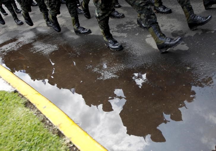 © Reuters. Soldiers in formation are reflected in a puddle of water during an event to celebrate the Day of the Soldier in Tegucigalpa