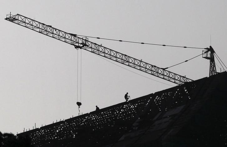 © Reuters. Labourers work on top of a construction site in Jinning