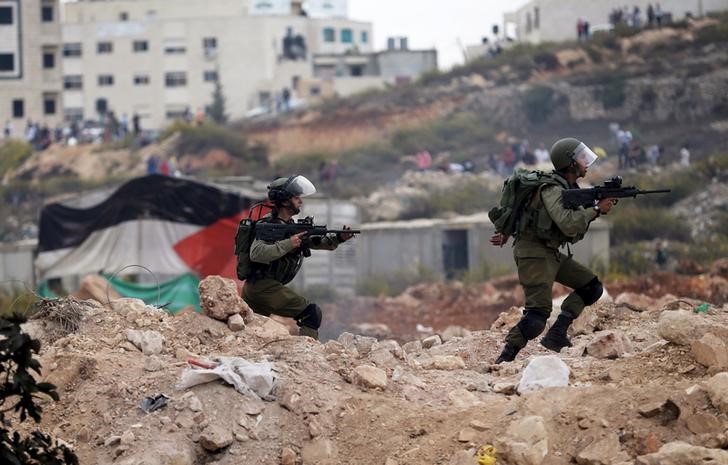 © Reuters. Soldados israelenses correm durante confronto com manifestantes palestinos