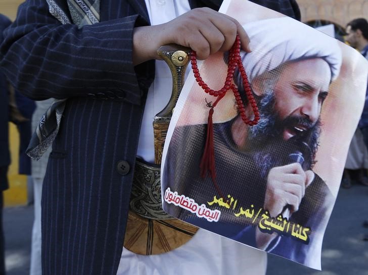 © Reuters. Shi'ite protester carries a poster of Sheikh Nimr al-Nimr during a demonstration outside the Saudi embassy in Sanaa