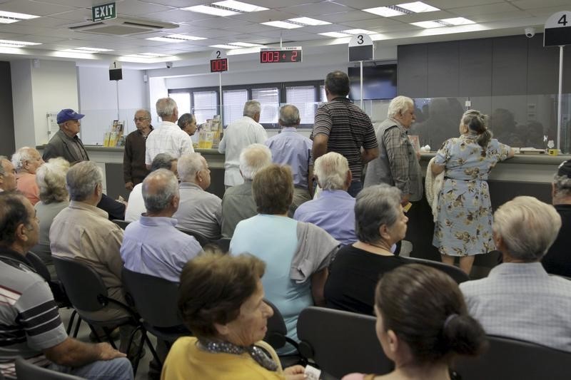 © Reuters. People wait inside a Piraeus Bank branch at the city of Iraklio in the island of Crete