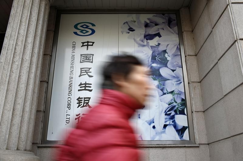 © Reuters. A woman walks past a branch of China Minsheng Bank in Shanghai