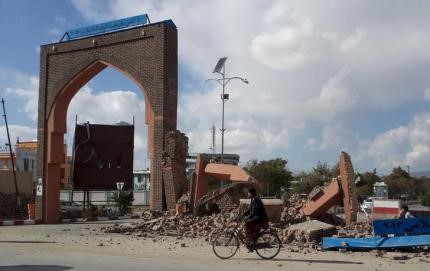 © Reuters. A man rides his bicycle next to damaged structures, after an earthquake in Ghazni, Afghanistan