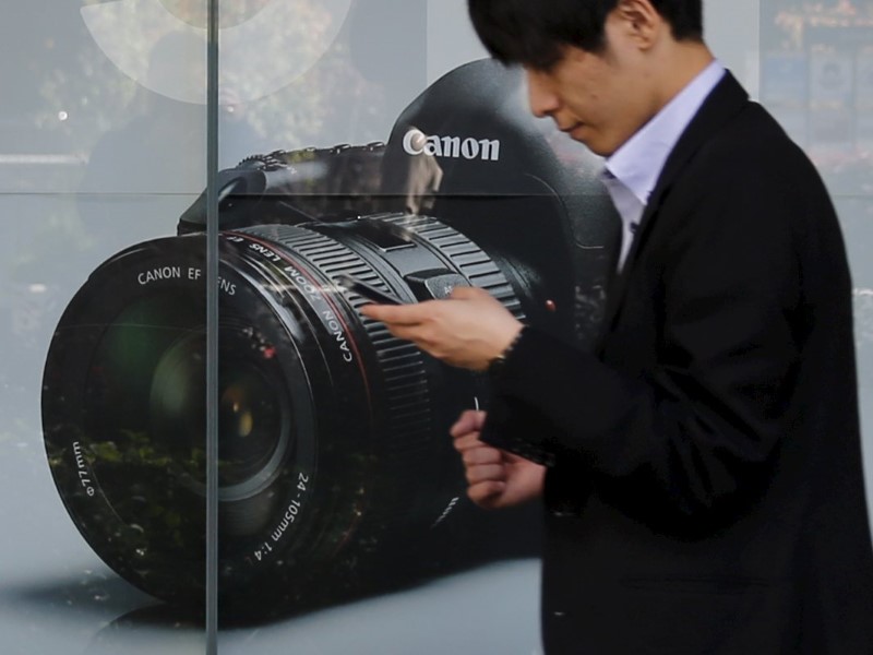 © Reuters. A man walks past an advertisement for a Canon digital camera in Tokyo