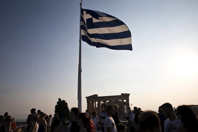 © Reuters. Greek flag flutters in the wind above tourists visiting the archaeological site of the Acropolis hill in Athens, Greece