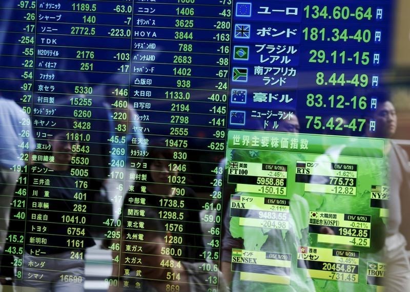 © Reuters. Passersby are reflected on a screen displaying  stock quotation, the stock market indices of various countrie and  exchange rates  at a brokerage in Tokyo