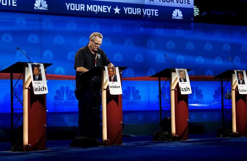 © Reuters. A technician works on the podium for Huckabee for tomorrow's Republican presidential candidate debate on stage in Boulder