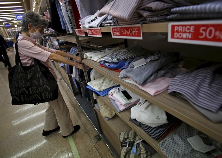 © Reuters. A woman wearing a mask looks at clothes at a retail store at a business district in Tokyo