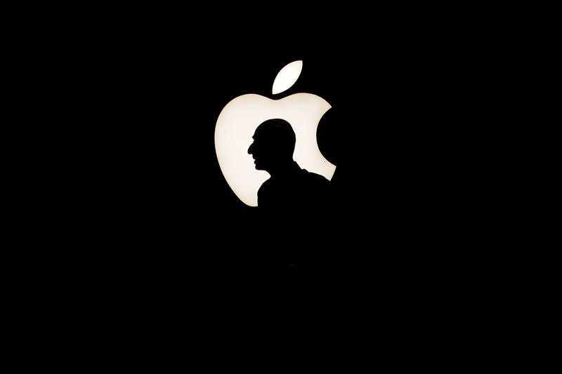 © Reuters. A man walks past a backlit Apple logo during an Apple media event in San Francisco