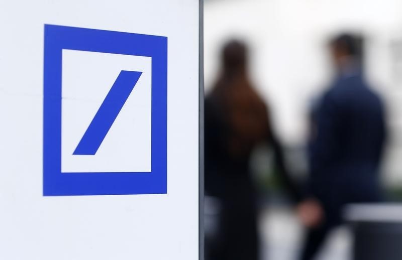 © Reuters. Pedestrians pass by a Deutsche Bank logo seen near the Deutsche Bank headquarters in Frankfurt