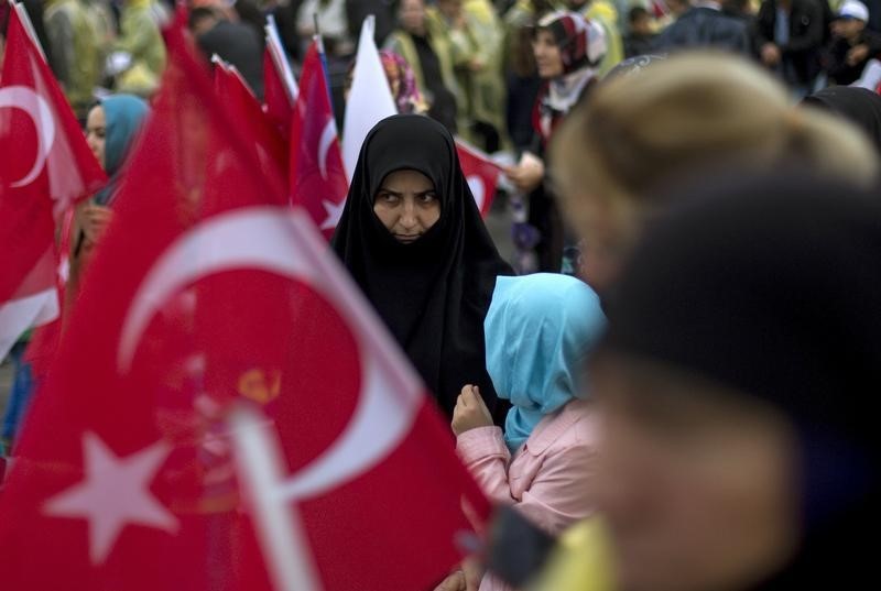 © Reuters. An AK Party supporter is seen through Turkish national flags during an election rally in Diyarbakir