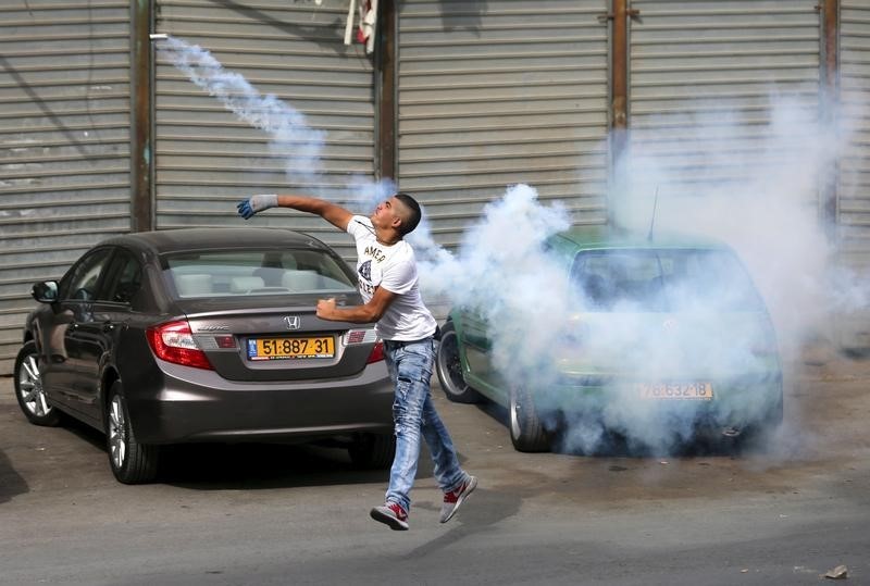 © Reuters.  Palestinian protester hurls back a tear gas canister fired by Israeli troops during clashes in the West Bank town of Al-Ram