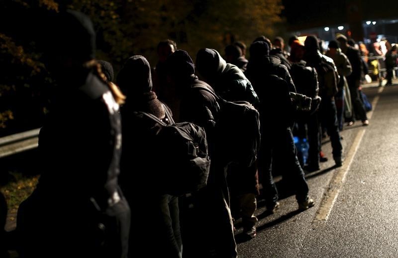 © Reuters. Migrants stay in a queue after crossing the Austrian-German border from Achleiten, Austria, in Passau