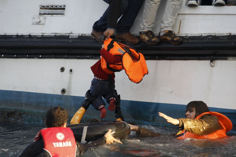 © Reuters. Homem retirando criança refugiada da água, próximo a ilha grega de Lesbos