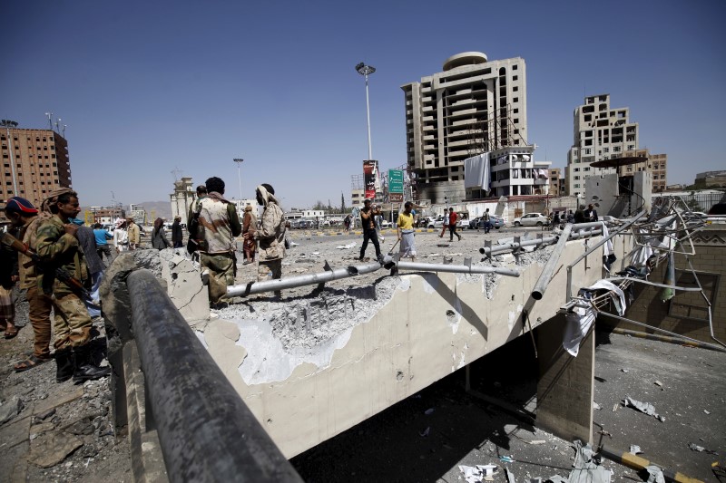 © Reuters. Houthi militants stand at the site of a Saudi-led air strike which targeted a tunnel leading to the presidential house near the Petrol Station in Yemen's capital Sanaa