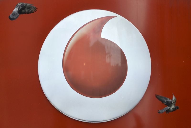 © Reuters. Pigeons fly past Vodafone branding outside a retail store in London