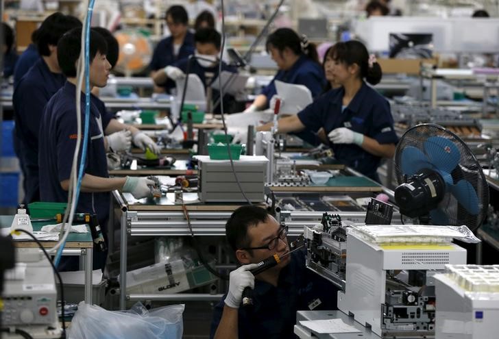 © Reuters. Employees work an assembly line at a factory of Glory Ltd., a manufacturer of automatic change dispensers, in Kazo, north of Tokyo