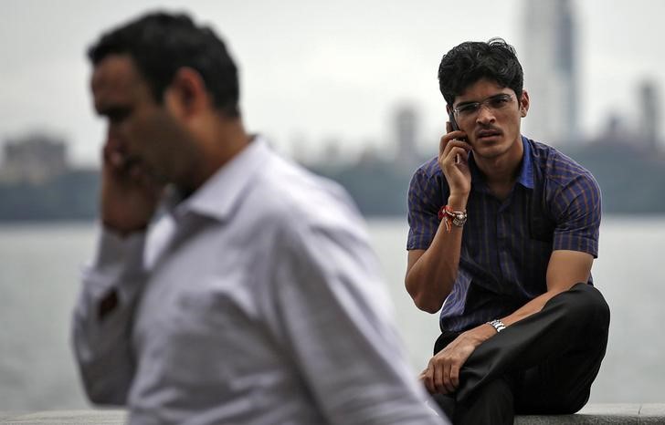 © Reuters. Мужчины говорят по телефону в Мумбаи