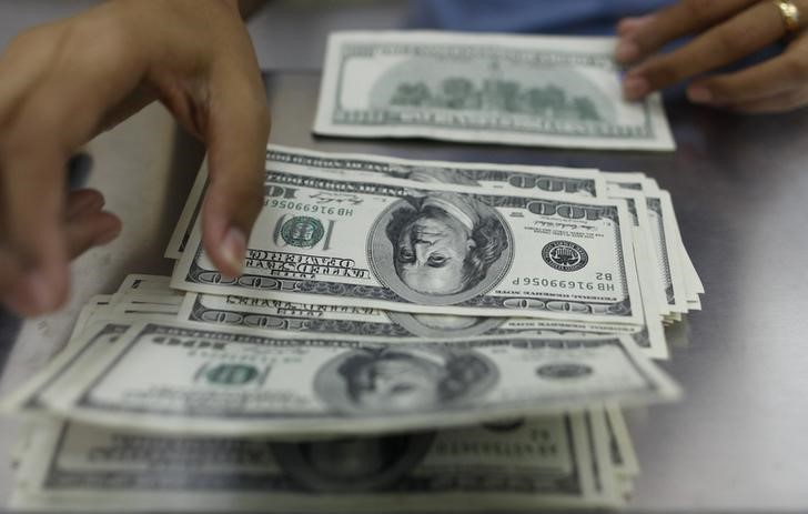 © Reuters. A woman counts U.S. dollars at a money changer in Yangon