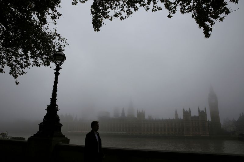 © Reuters. A man walks past the Big Ben clocktower and the Houses of Parliament during a foggy day in central London