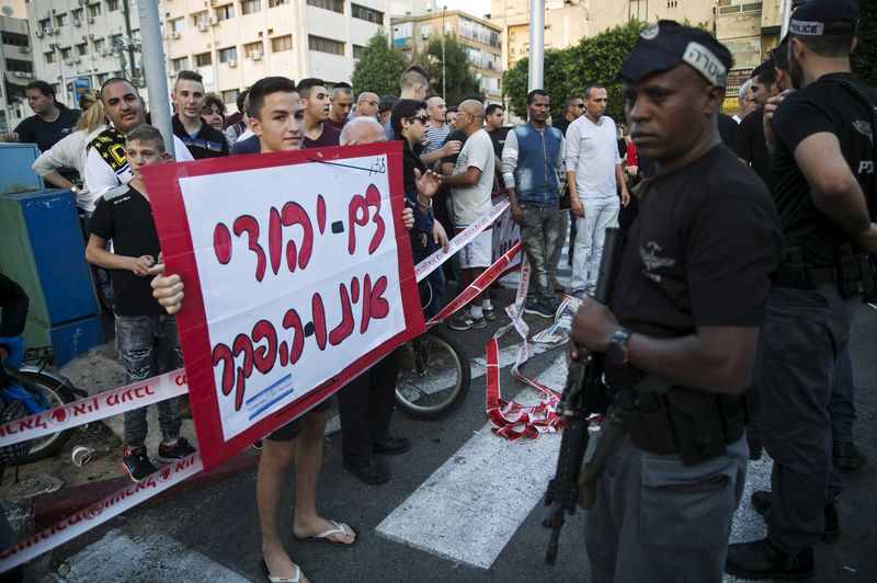 © Reuters. Israeli police stand next to a protester at the scene of a stabbing in Rishon Lezion near Tel Avi