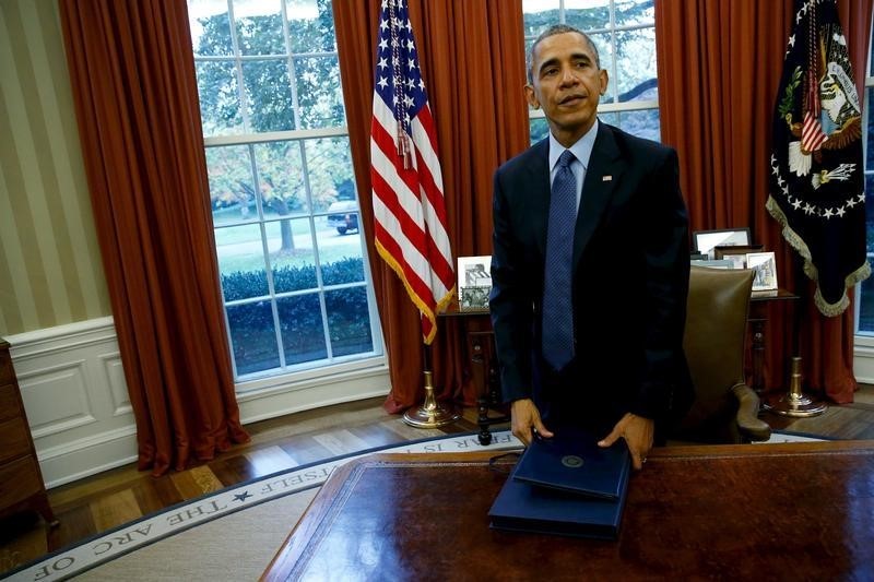 © Reuters. U.S. President Barack Obama collects the folio holding the Bipartisan Budget Act of 2015 after signing it into law in the Oval Office at the White House in Washington