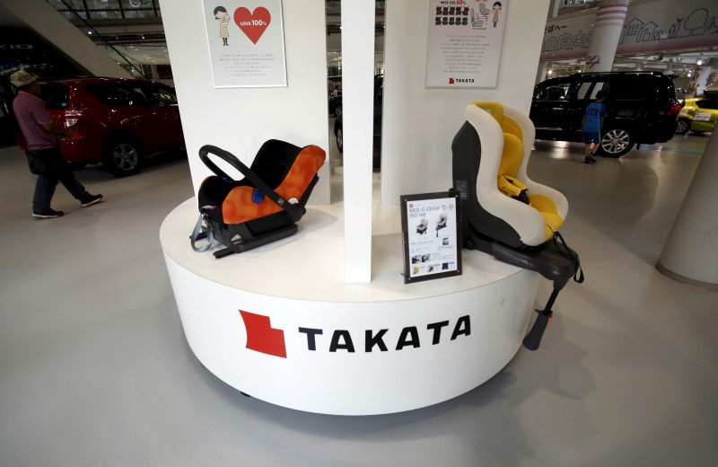 © Reuters. Visitors look at cars behind a logo of Takata Corp on its display at a showroom for vehicles in Tokyo