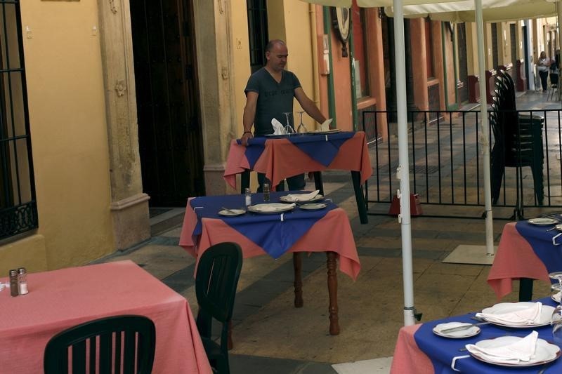 © Reuters. A waiter carries a table to place it at the terrace of a restaurant in downtown Ronda